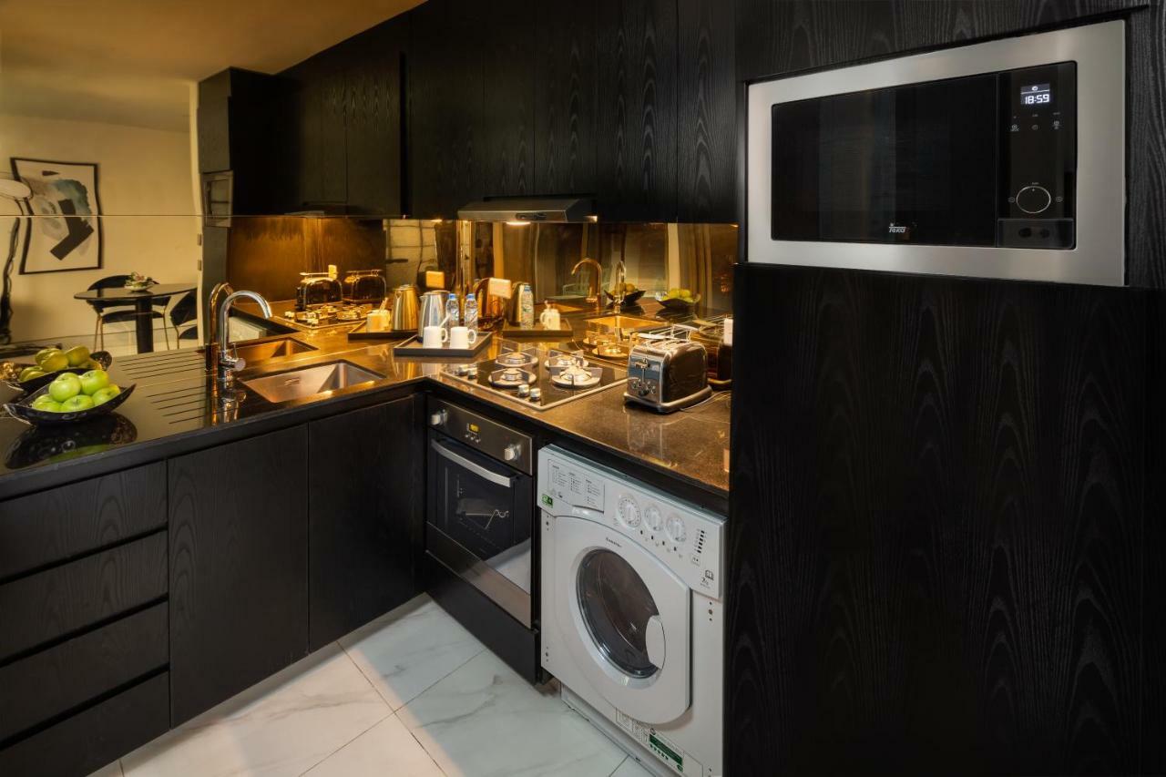 Апарт готель Millennium Atria Business Bay Дубай Екстер'єр фото The photo shows a modern kitchen with a sleek design. The cabinets and surfaces are predominantly black, creating a contemporary look. There is a stainless steel microwave mounted above the countertop, and on the counter, various kitchen appliances l